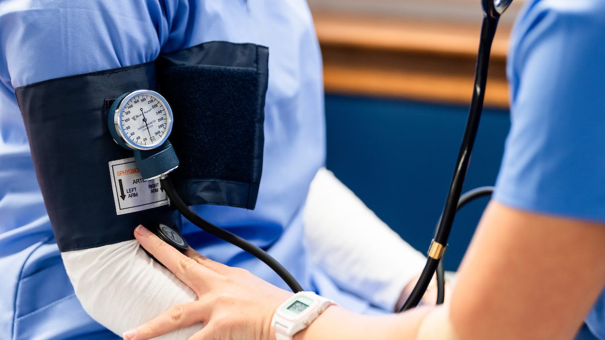 A photo of a nursing checking another nurse's blood pressure