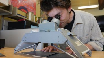 A photo of a person looking through a magnifier at an image