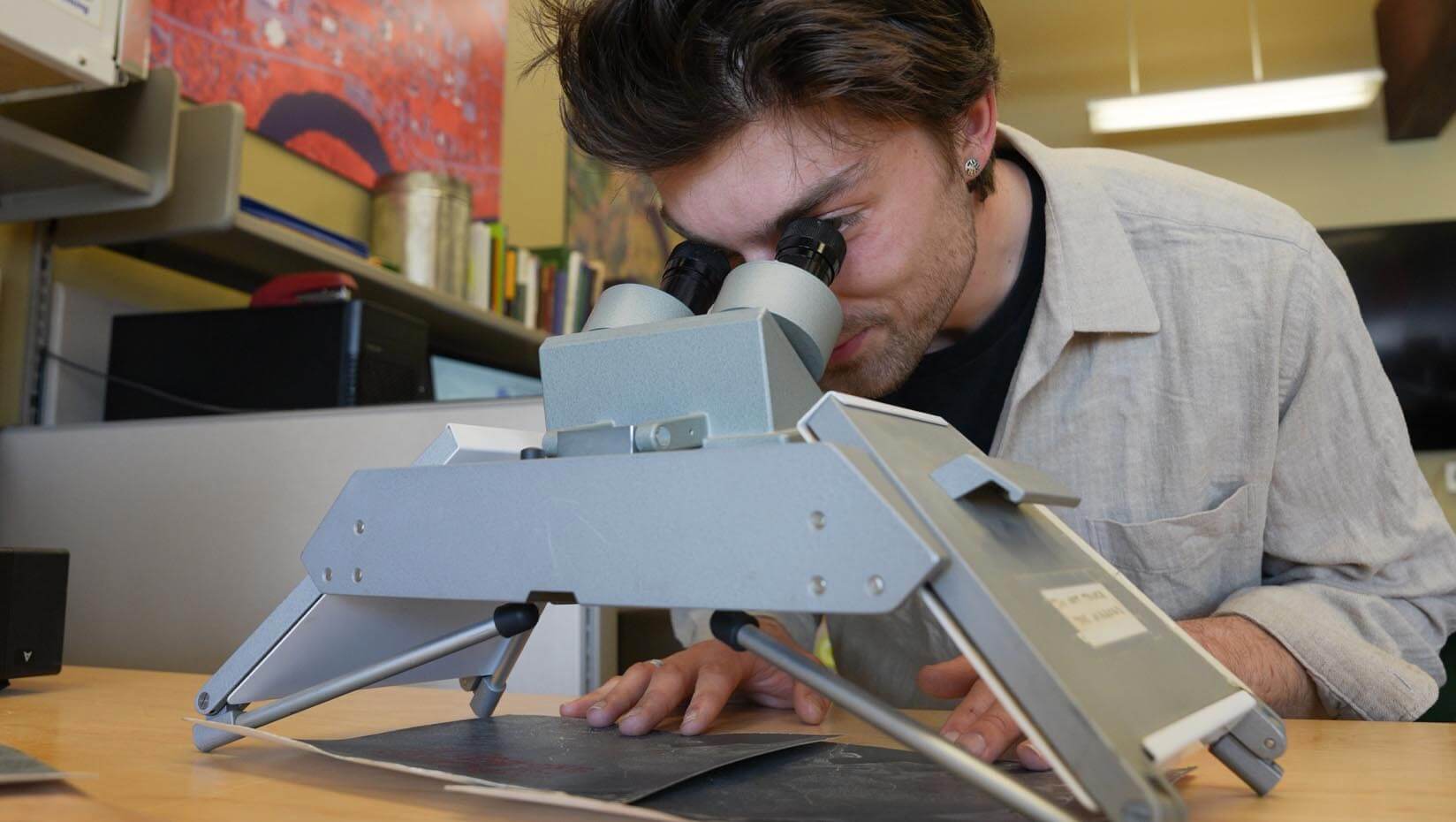 A photo of a person looking through a magnifier at an image