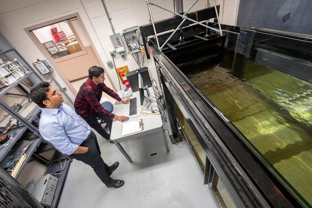 A photo of two researchers standing in front of a tank