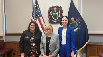 A photo of three people smiling while posting for a picture.