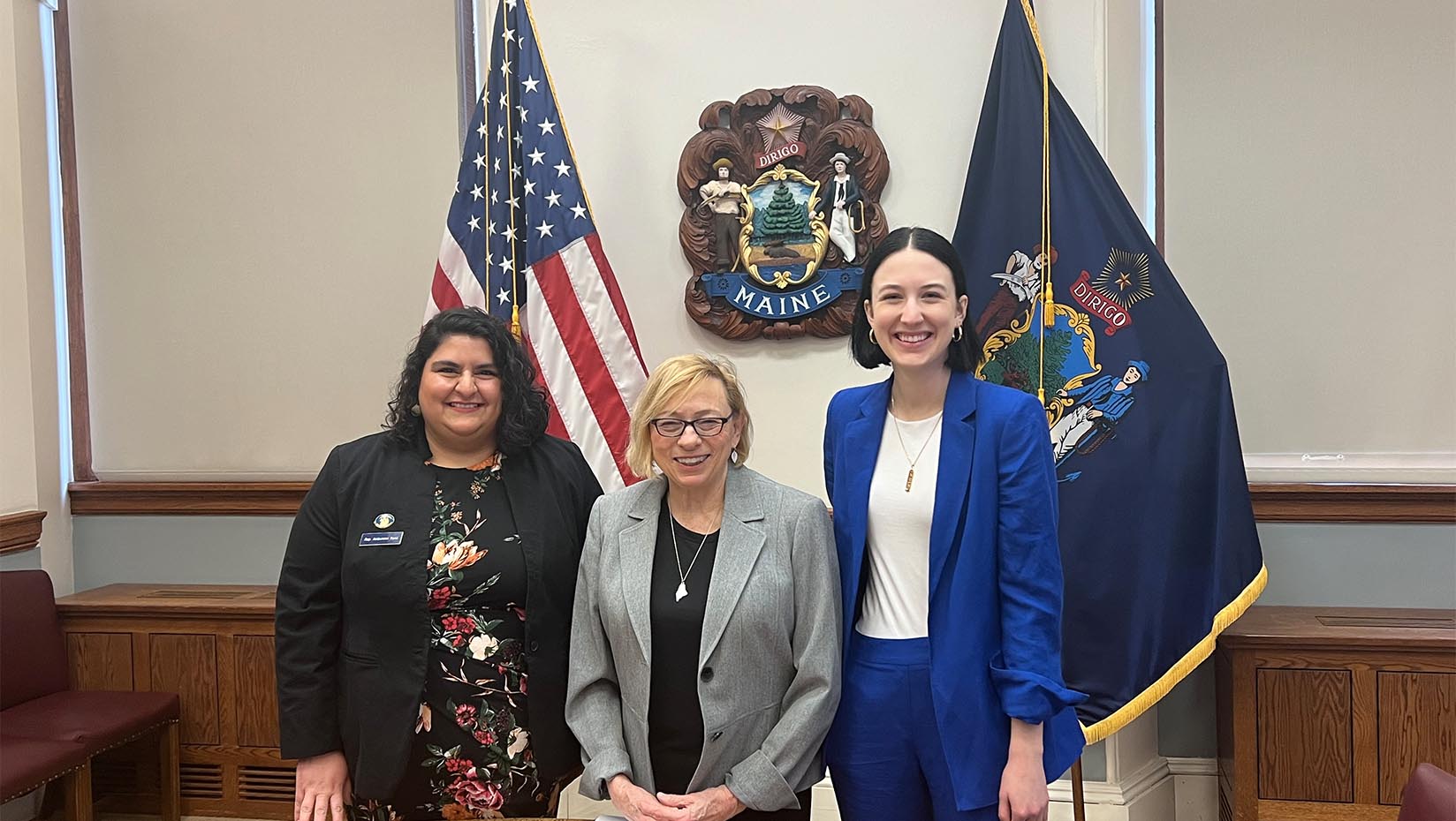 A photo of three people smiling while posting for a picture.
