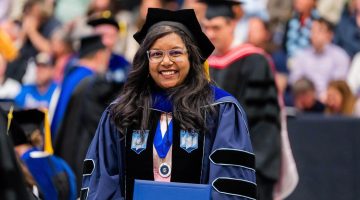 A photo of a doctoral graduate holding their diploma