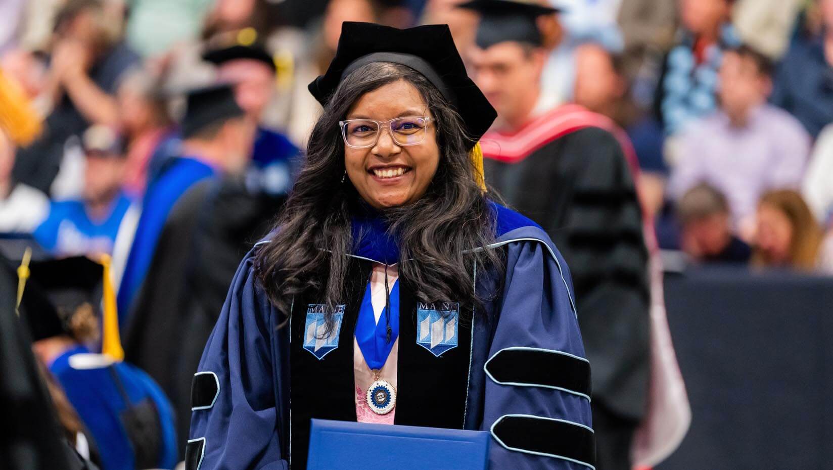 A photo of a doctoral graduate holding their diploma