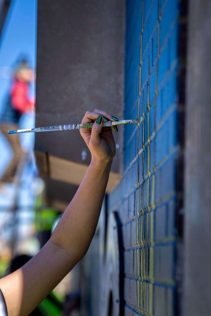 A photo of a hand painting a wall