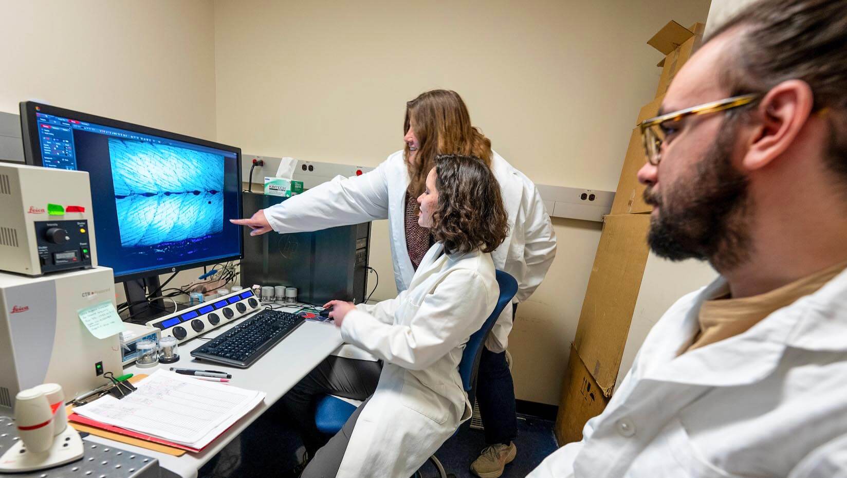 A photo of two grad students and a professor in a lab