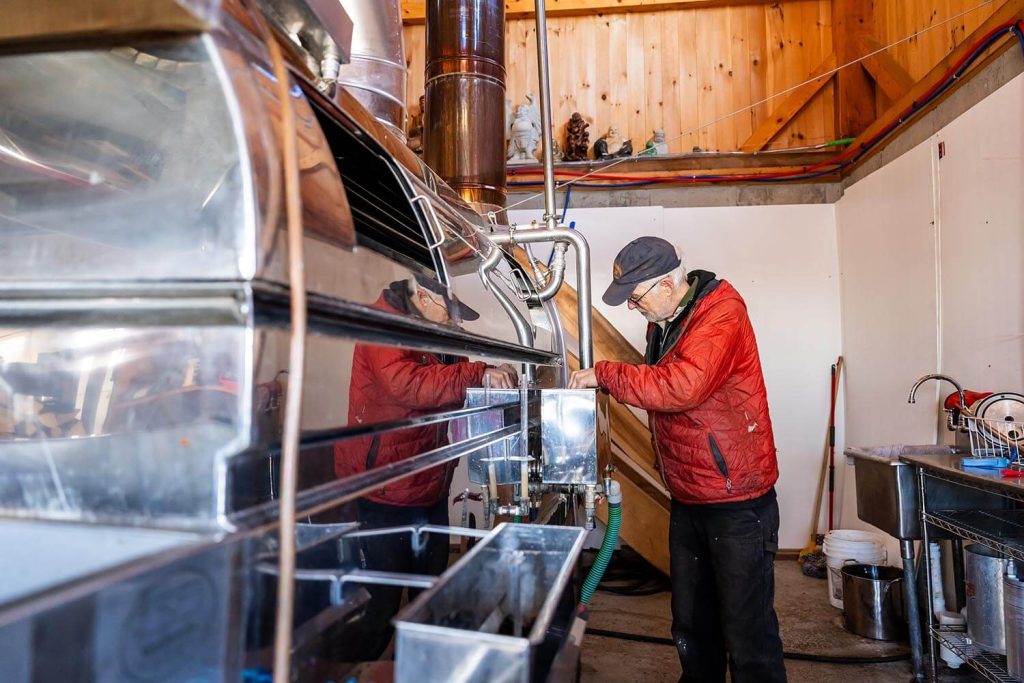A photo of a person and some maple syrup processing machines