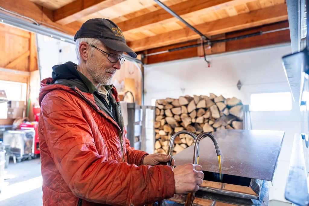 A photo of a person with some taps that are pouring some maple syrup