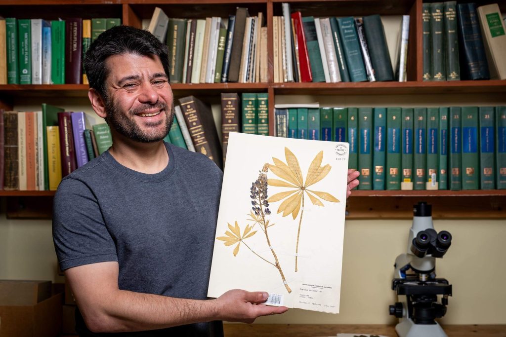 A photo of Jose Eduardo Meireles holding a preserved plant