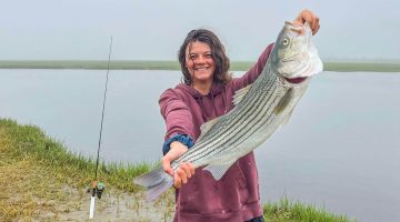 A photo of Abby Remick holding a stripped bass