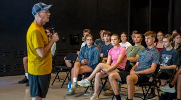 A photo of high school students listening to a speaker