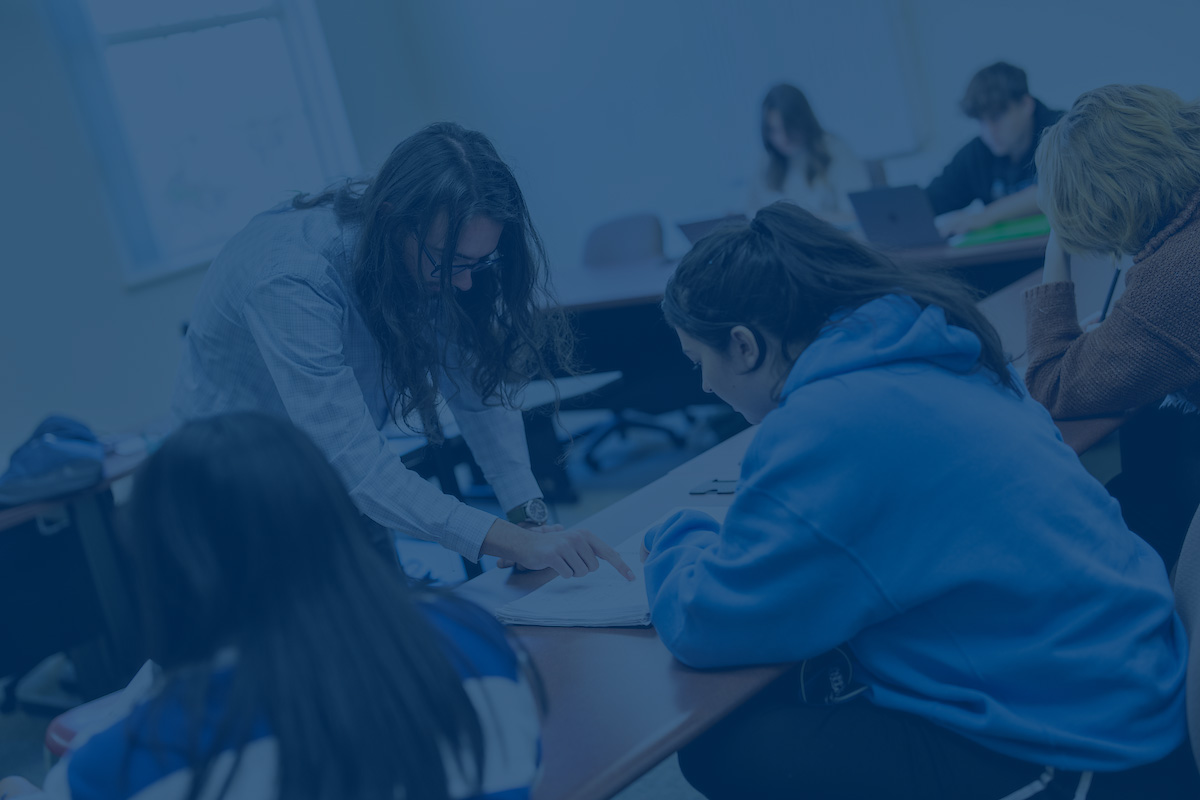 A photo of students in a class with a blue overlay. Link to Student Support Services website