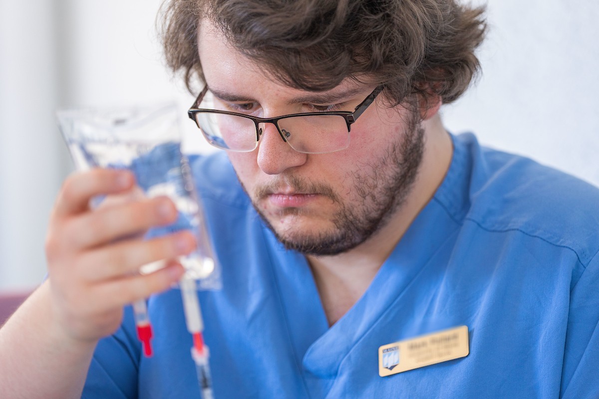 A photo of a nursing student focusing on a fluid bag