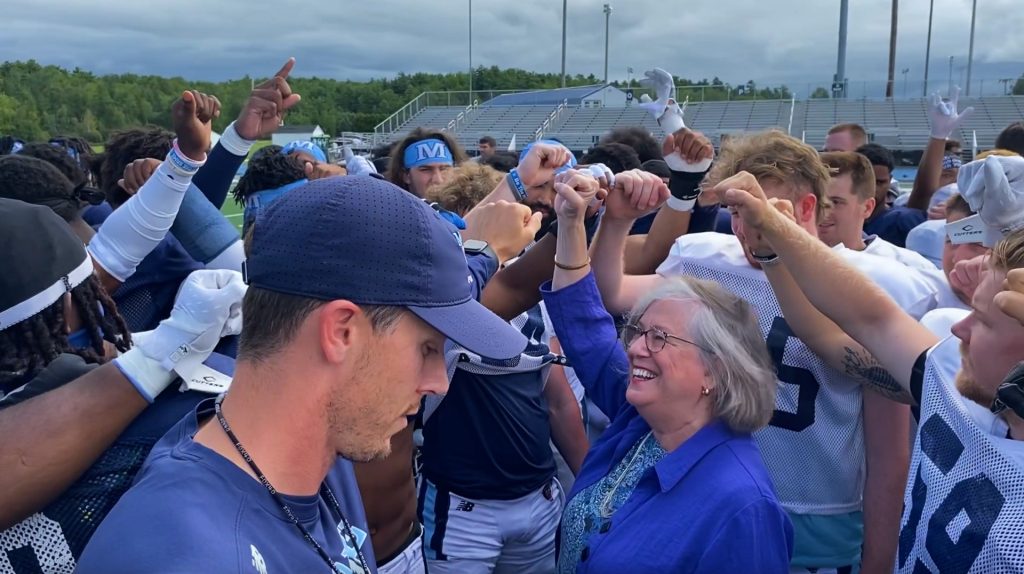A photo of President Ferrini-Mundy with the UMaine football team
