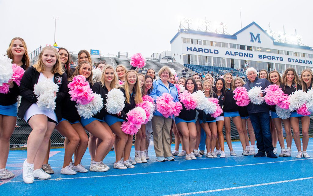 A photo of President Ferrini-Mundy and Robert Dana with UMaine cheerleaders