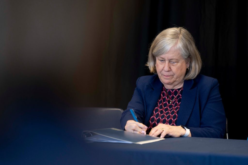 A photo of President Ferrini-Mundy signing a document