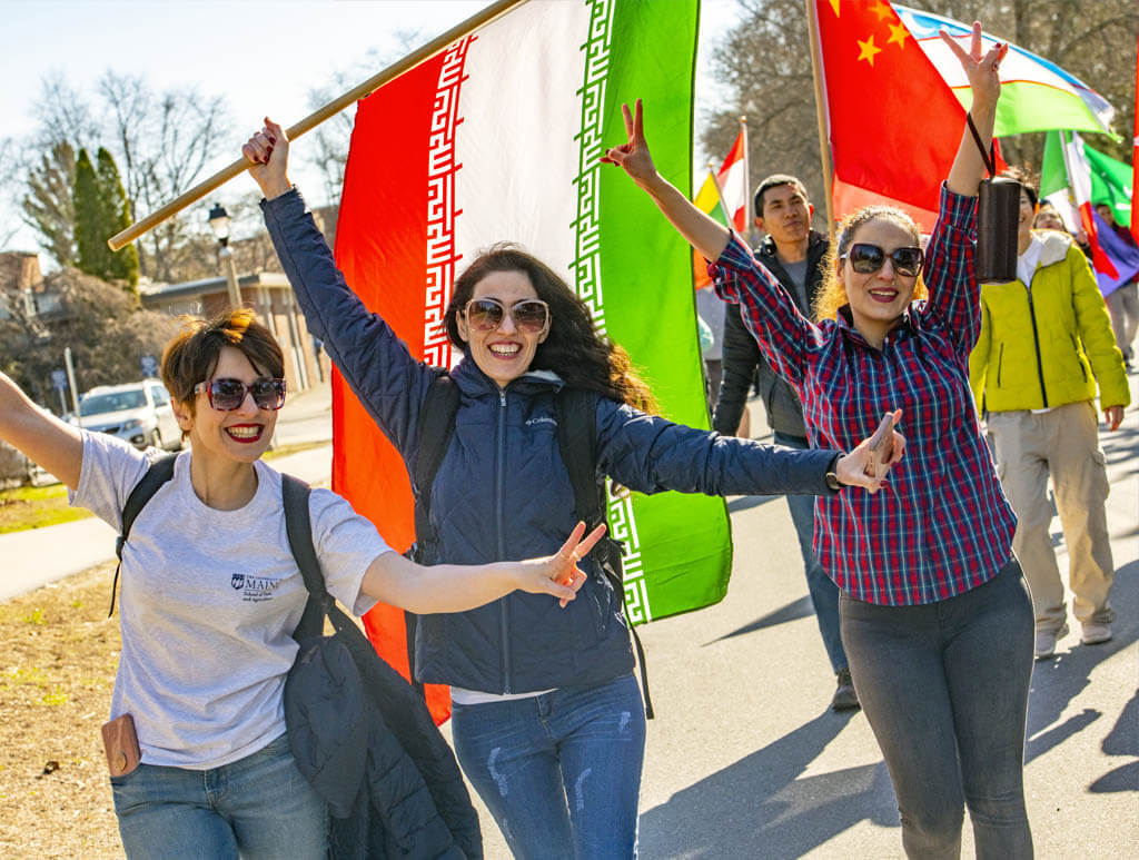 A photo of women holding international flags and making peace signs with their hands