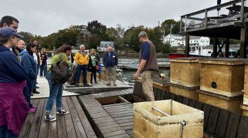 Image of people listening to a presentation from a fisherman