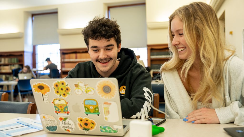 Two students collaborate at a laptop in Fogler Library.