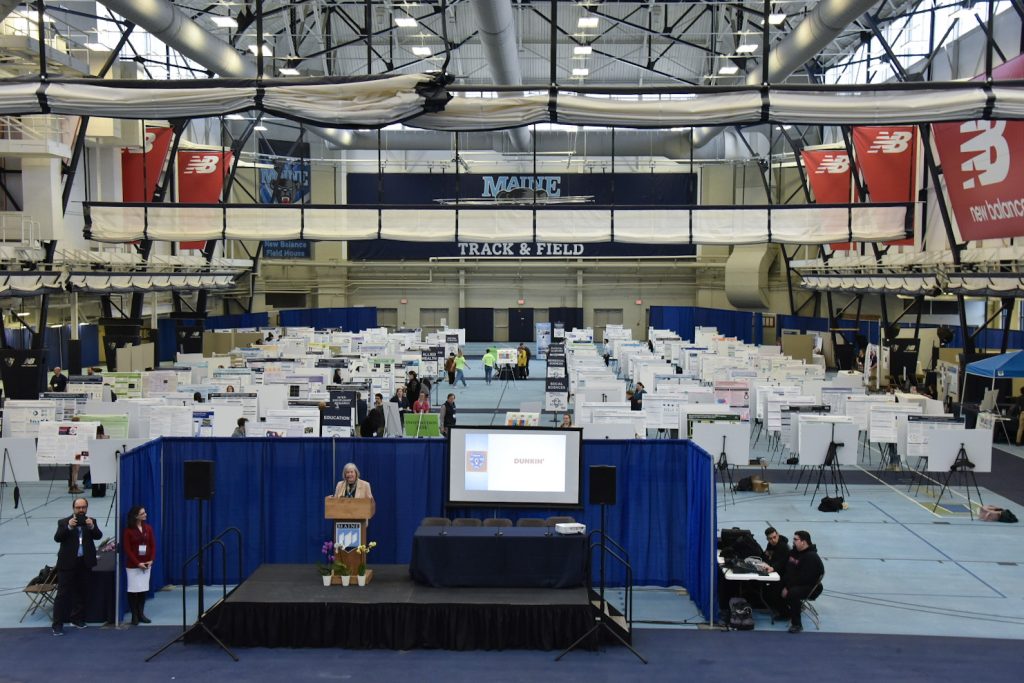 Wide shot of UMSS24 Presentation floor. Attendees walking around venue, looking at poster and exhibit presentations.