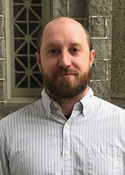 Headshot of Dr. Benjamin Guenther. He is wearing a striped button-up shirt.